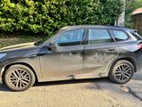 the bmw x1 is parked on the side of the road in front of a house