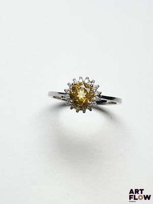 un gros plan d'une bague sertie d'un diamant jaune sur une surface blanche