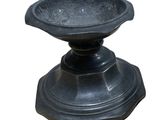 un bol en pierre noire posé sur un socle, sur fond blanc
