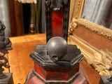 a red and black statue on a table with a mirror in the background
