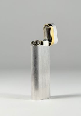un gros plan d'un briquet posé sur une surface blanche, avec un arrière-plan gris