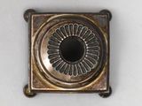 a small metal object with a circular design on it