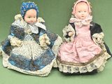 two dolls that are sitting next to each other on a green surface