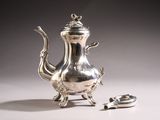 a silver tea pot sitting on a table next to a spoon