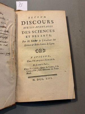 un livre ouvert posé sur une table, avec une feuille de papier dessus