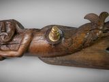 wooden sculpture of a woman laying on a wooden plank with a candle in her hand