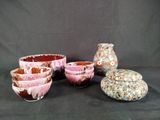 five bowls and a vase sitting on a black background