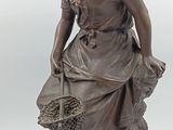 statue en bronze représentant une femme tenant un panier de fleurs, posée sur un socle