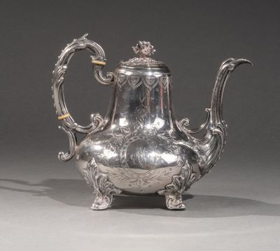 une théière ancienne en argent, ornée de motifs élaborés sur fond gris