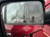 une voiture rouge avec un rétroviseur cassé, garée sur le bord de la route