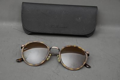des lunettes de soleil et leur étui posés sur une table à côté d'une paire de lunettes