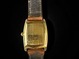 a close up of a watch on a black surface with a black background