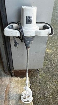 a white electric drill sitting on the side of a building