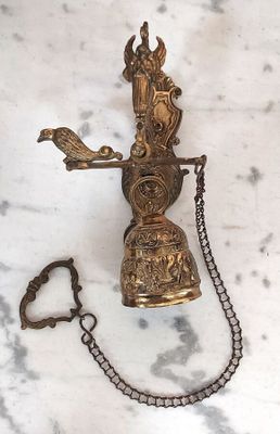 a brass bell with a chain around it on a marble surface