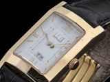 a close up of a gold watch with a black leather band