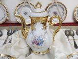 a white and gold tea pot and silver spoons on a table