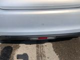 the rear end of a silver car parked in a parking lot
