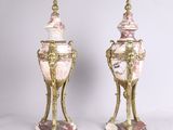 une paire de vases anciens roses et dorés posés sur des socles, sur fond blanc