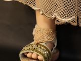 a close up of a doll ' s foot wearing a pair of sandals