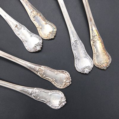 five silver spoons and two silver spoons on a black surface
