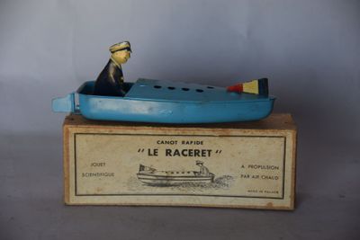 un petit bateau bleu avec un homme à l'intérieur, posé sur une caisse