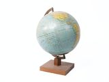 un petit globe posé sur un socle en bois, lui-même posé sur une surface blanche