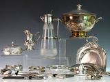 de nombreux objets en argent posés sur une table, sur fond gris