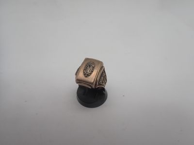 une bague en argent ornée d'une croix, posée sur un socle noir