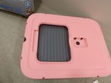 a pink plastic box with a window on top of a couch