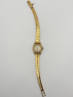 gros plan d'une montre-bracelet en or sur une surface blanche