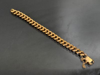 gros plan d'un bracelet en chaîne en or sur une surface noire