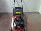 a red lawn mower sitting on the floor in a garage