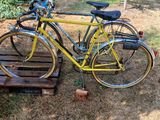 a yellow bicycle parked next to a wooden bench