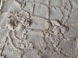 a crocheted table cloth on a bed next to a crocheted doily