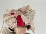 a small doll with a red bow on it ' s head