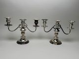 two silver plated candlesticks with candles on each of them