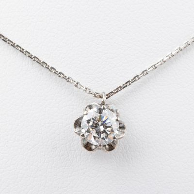 a diamond pendant on a chain on a white surface