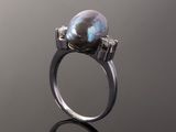 a close up of a ring with a pearl and diamonds on it