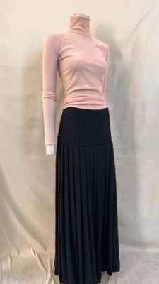 jupe plissée noire avec un pull à col roulé rose
