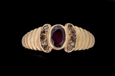 gros plan d'une bague en or avec une pierre en rubis