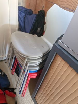 a pile of luggage sitting on the floor next to a stack of chairs