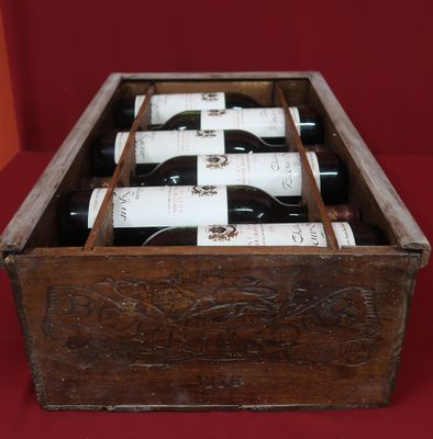 bottles of wine are in a wooden box on a red surface