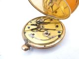a gold pocket watch sitting open on a white surface