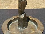 a bronze bird on a metal plate on a table