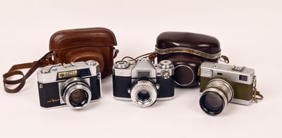 four cameras are lined up in a row on a white surface