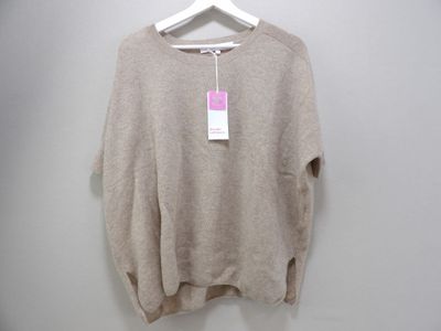 the sweater is hanging on a hanger on a white wall