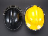 yellow hard hat and black hard hat sitting side by side