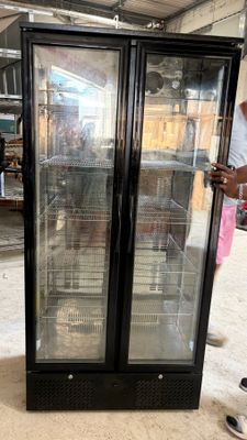a man standing in front of a glass door refrigerator