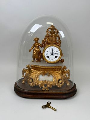 a gold clock under a glass dome on a table