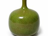 un vase vert posé sur une surface blanche